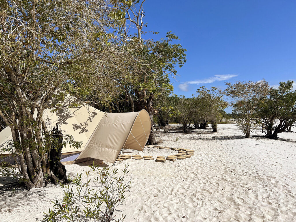 Stylish tented camp set on a pristine riverfront beach in the Amazon rainforest, featuring canvas tents with outdoor seating, surrounded by lush greenery and natural beauty.